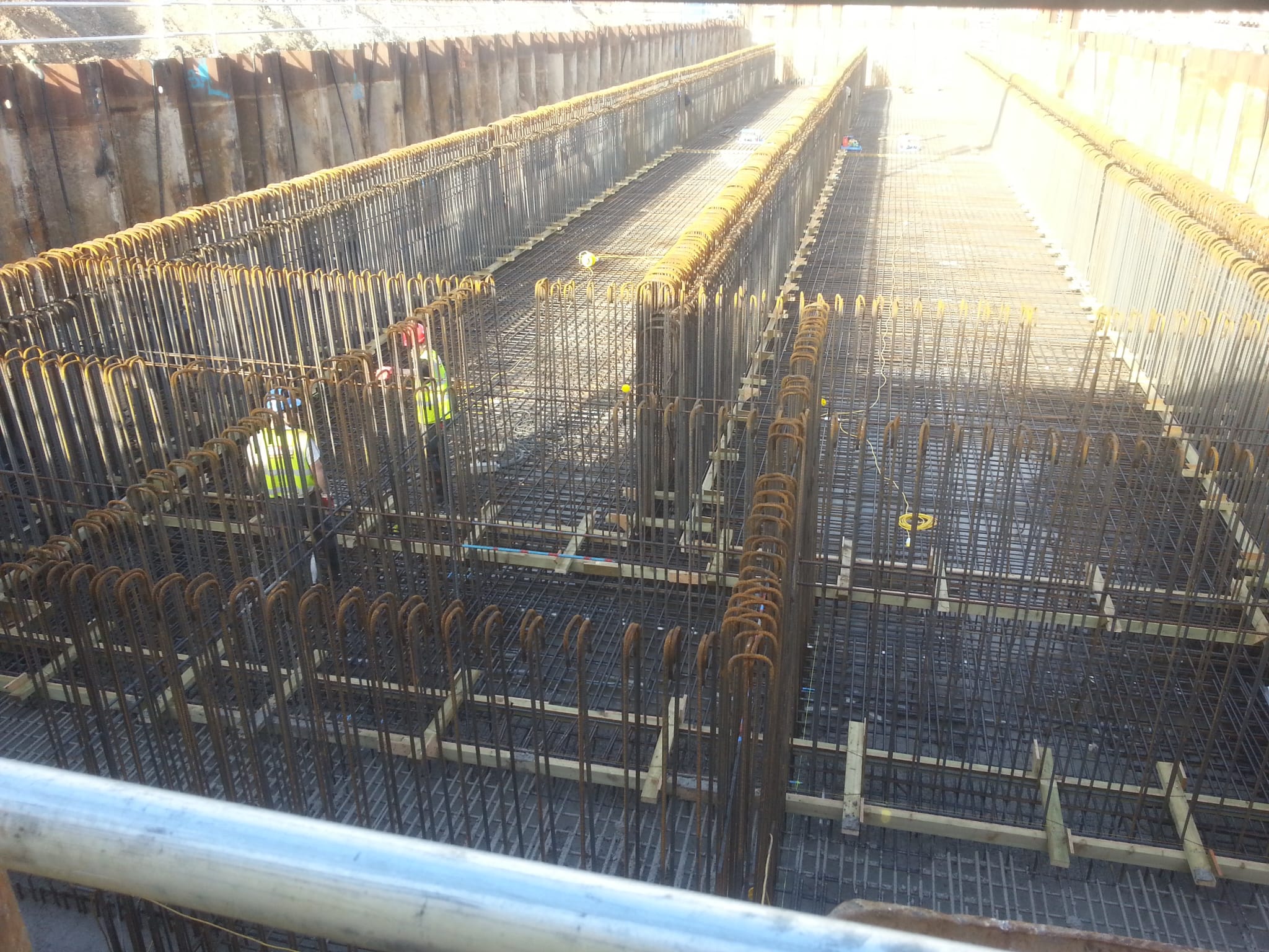 Multi-bay foundation reinforcement walls in a steel sheet piled excavation with crews working